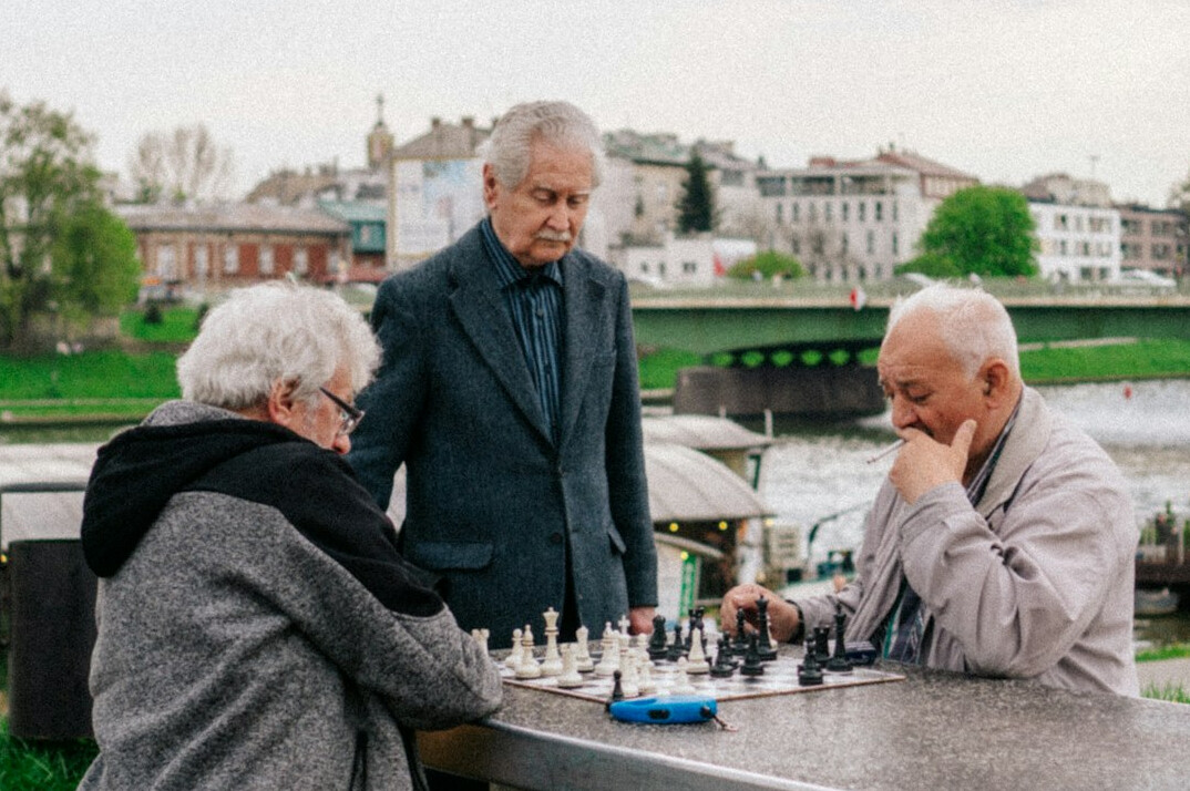 Two elderly men playing chess at a community center table